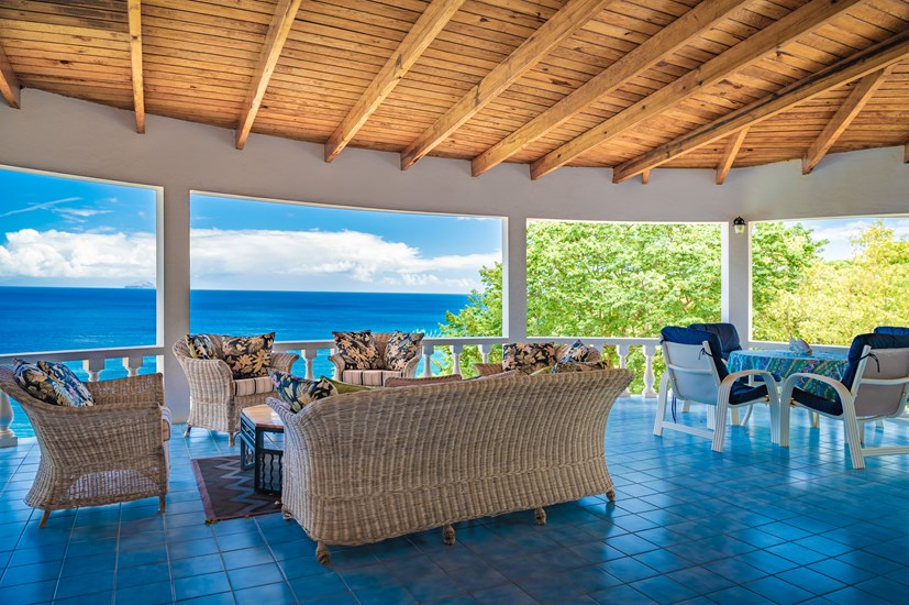 Table and chairs on a veranda overlooking the blue ocean and sky 